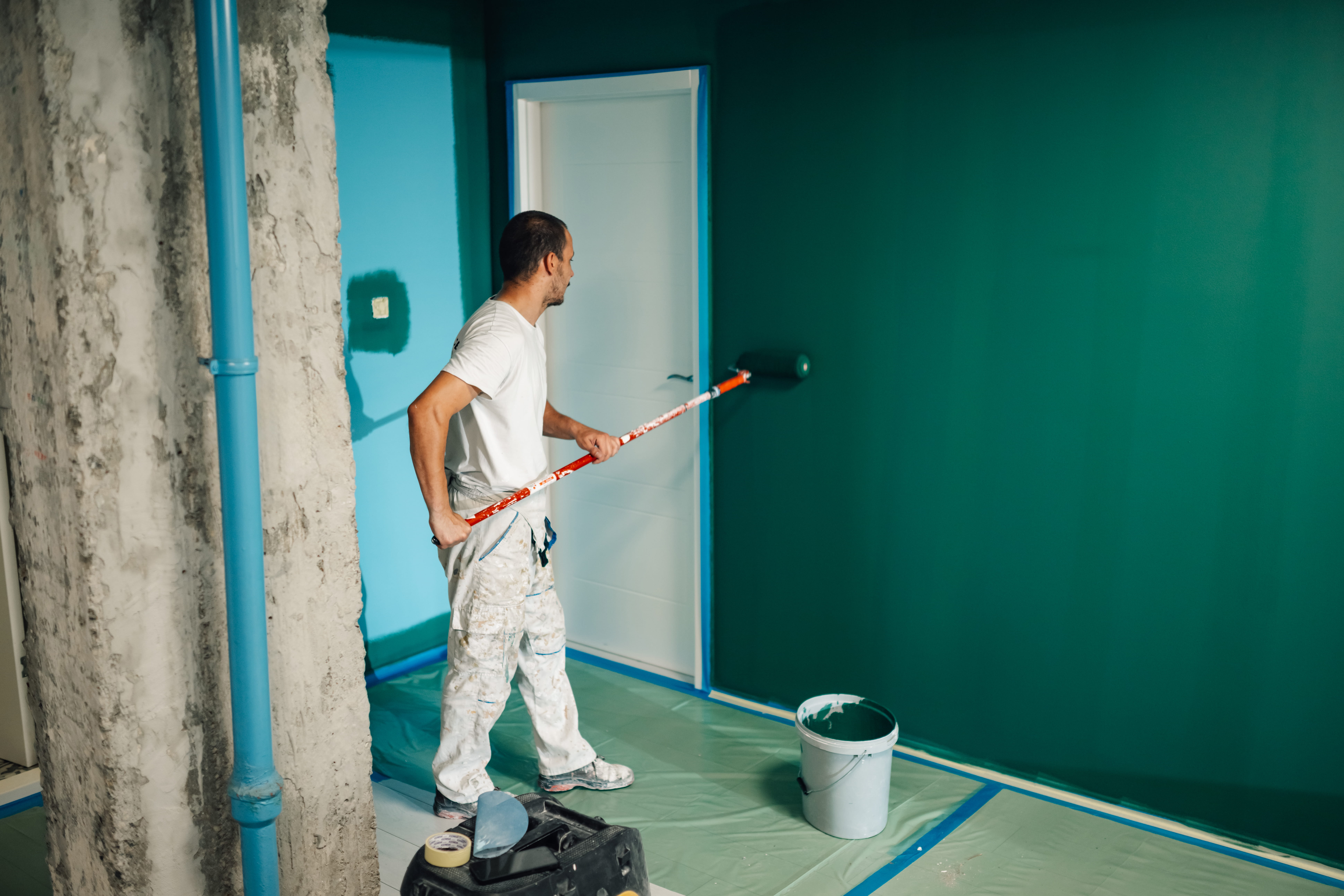 Painter rolling a decorative green wall